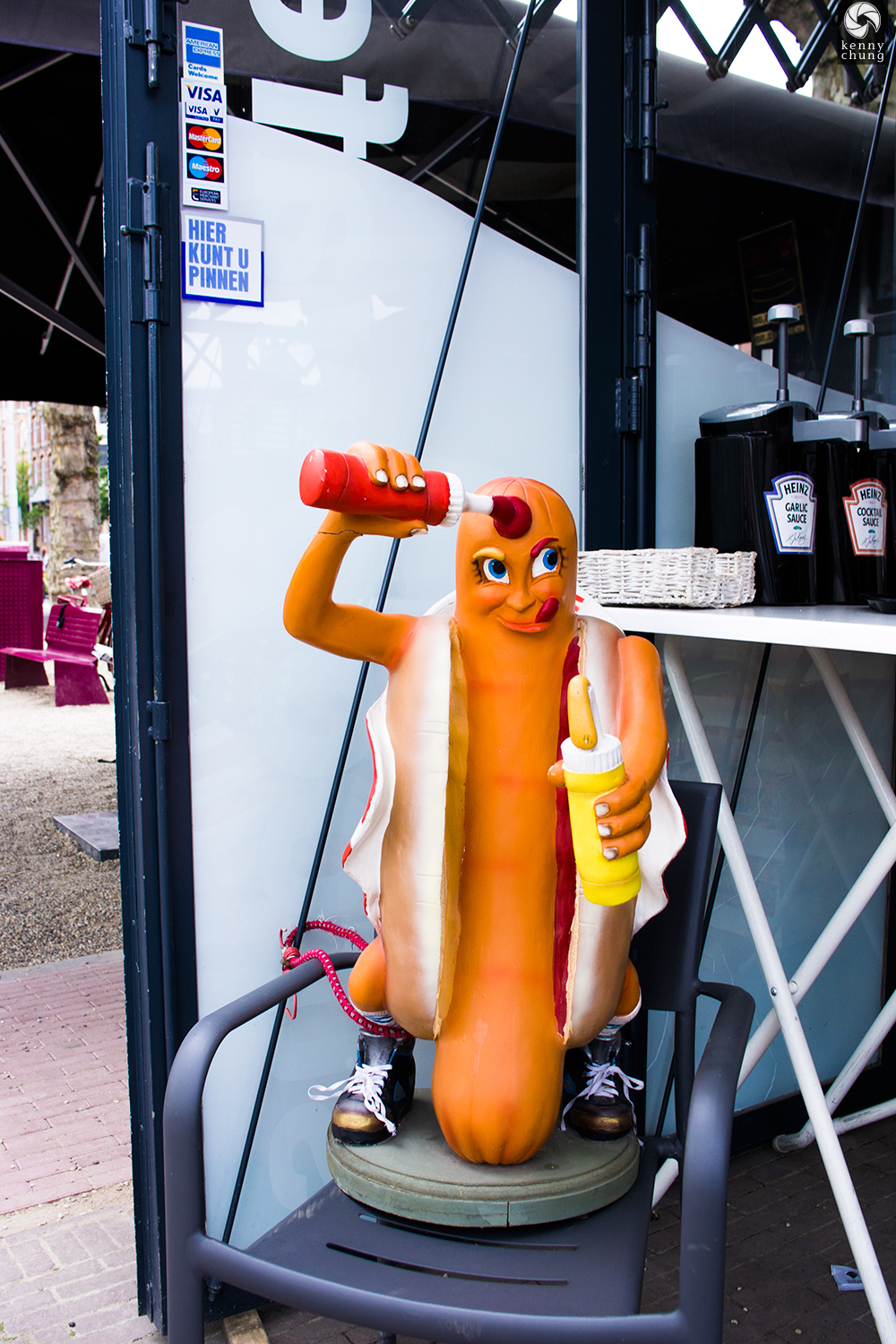 A statue of a hot dog putting sauce on himself