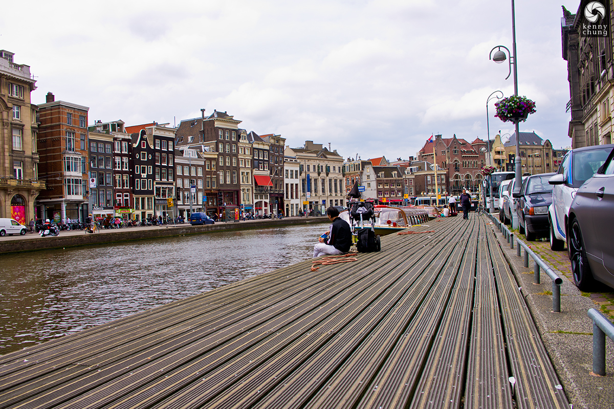 Man sitting on the boardwalk on the canal in Amsterdam