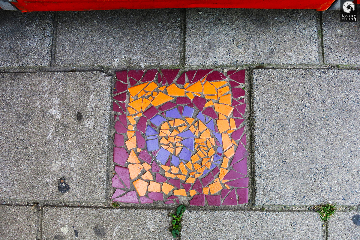A street mosaic embedded into the sidewalk in Amsterdam