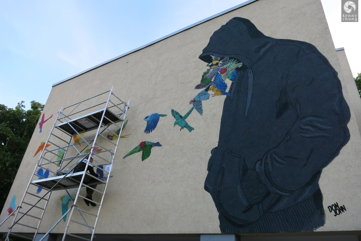 Street art by Don John of birds flying out of a hoodie