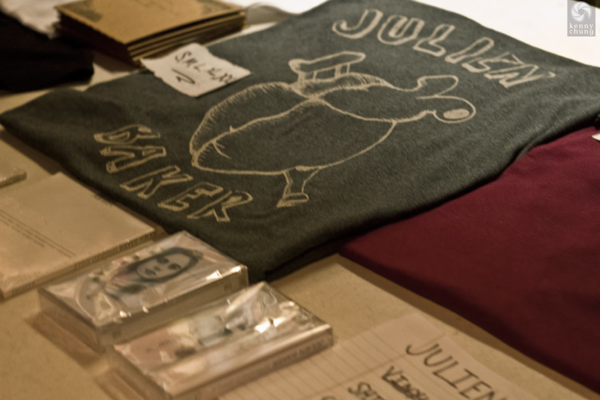 A few pieces of Julien Baker merchandise, including a t-shirt and her debut album Sprained Ankle on cassette tape
